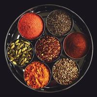 Set of indian spices in metal bowls on black background