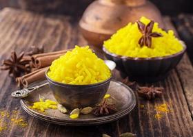 Bright yellow boiled rice with turmeric and aromatic spices on photo