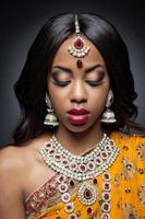mujer india en vestimentas tradicionales con maquillaje de novia y joyas foto