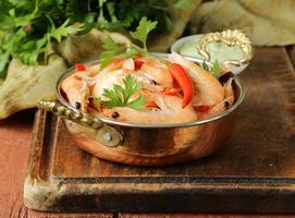 fried prawns with chilli in a copper pan, Indian style photo