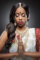 mujer india en vestimentas tradicionales con maquillaje de novia y joyas foto