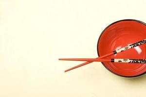 Tazón vacío rojo de estilo asiático con palillos en bakcground de seda. foto