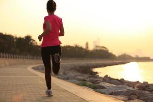 joven fitness mujer corriendo en la playa del amanecer foto