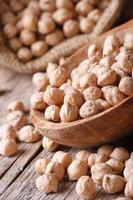 Raw chickpeas in a wooden spoon macro vertical