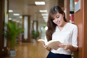 asian beautiful female student holding book in library portrait