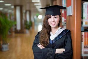 Hermosa estudiante asiática vistiendo traje académico en la biblioteca