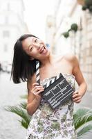 Young asian woman smiling shows clapper board photo