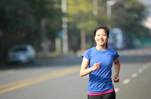 fit sports woman running on asphalt road photo