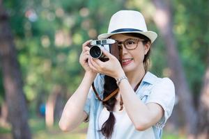 Hermosa chica asiática sonriendo con cámara retro fotografiando, ou