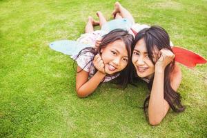two indonesian sisters lying down on a grass photo