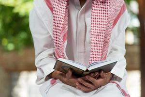hombre musulmán en dishdasha está leyendo el Corán
