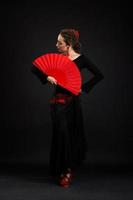 Young spanish woman dancing flamenco on black