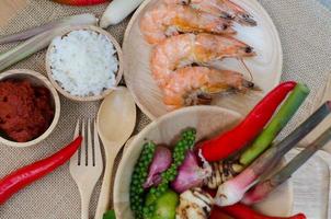 spices in bowl and prawn on sackcloth background photo