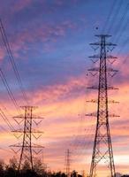 Parallel high voltage electricity pylon on the orange sky. photo