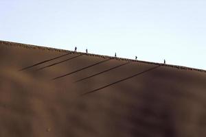 Personas en una duna roja en sossusvlei, namibia