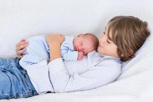 Newborn baby boy sleeping in the arms of his brother photo