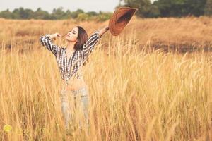 Beautiful asian girl holding a cowboy hat in the prairie photo