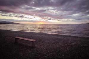 Empty bench on beach at sunset, marsala toned photo