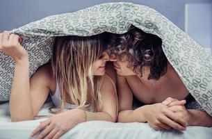Happy young couple in love kissing under duvet cover photo