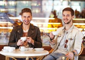 Dos hombres jóvenes / estudiantes usando tableta en café