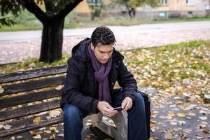Man traveler with mobile phone sitting on bench