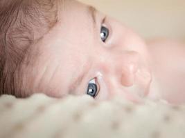 Portrait of newborn baby lying down over a blanket photo