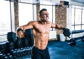 Muscular man lifting dumbbells