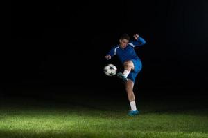 Professional Soccer Player Kicking Ball Isolated On Black photo