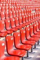 Red chairs bleachers in large stadium photo