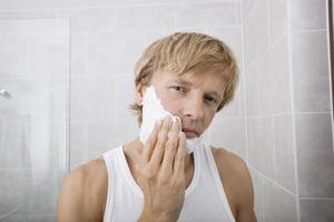 Retrato de hombre de mediana edad aplicando crema de afeitar en el baño.