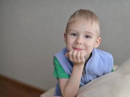 Young boy sitting on sofa looking at camera photo