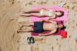 chico y novia descansando en la arena foto