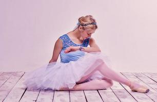 bailarina de ballet cansado sentado en el piso de madera foto