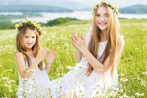 Two friends girls at meadow of chamomiles photo