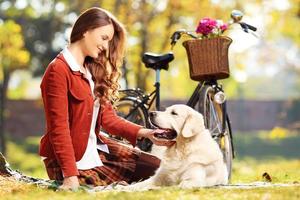 Beautiful female sitting on a grass with her dog