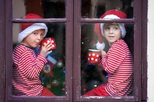 Two cute boys, brothers, looking through window, waiting Santa