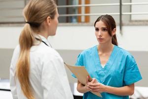 Nurse holding file and talking to doctor photo