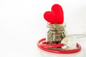 Stethoscope wrapped around a jar of coins with heart on it photo