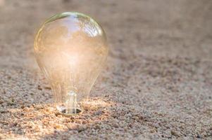 Natural energy concept of lightbulb on beach photo