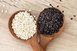Black and white sesame seeds in wooden spoons photo