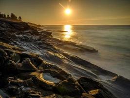 larga exposición de las olas del océano en la playa rocosa foto