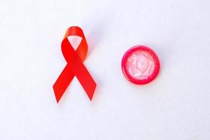Red ribbon and condom on white background photo