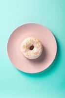 Vanilla donut with sprinkles on pink plate photo