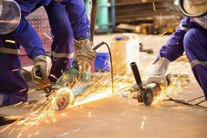 Workers cutting metal sheet with electric grinder photo