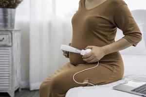 hermosa mujer embarazada asiática comparte música con bebé