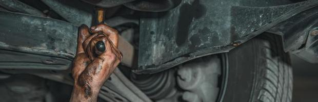 Greasy mechanic hand reaches under hood photo