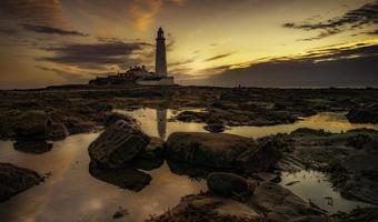 Lighthouse on rocky shore during sunset photo