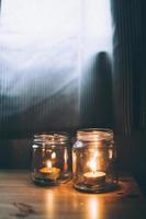 Two candles burning in glass jars photo