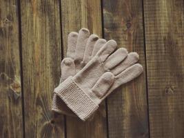 White knitted gloves on wooden surface photo