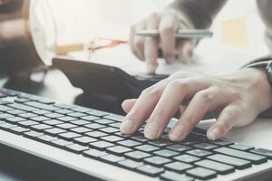 Business professional typing on keyboard while using calculator  photo